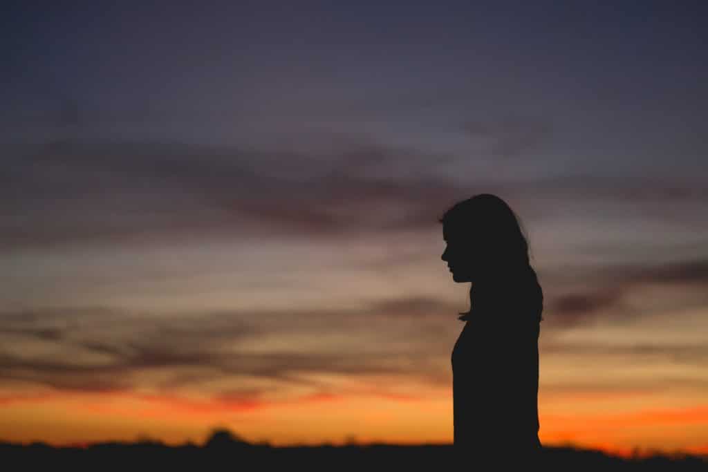 woman standing alone at sunset